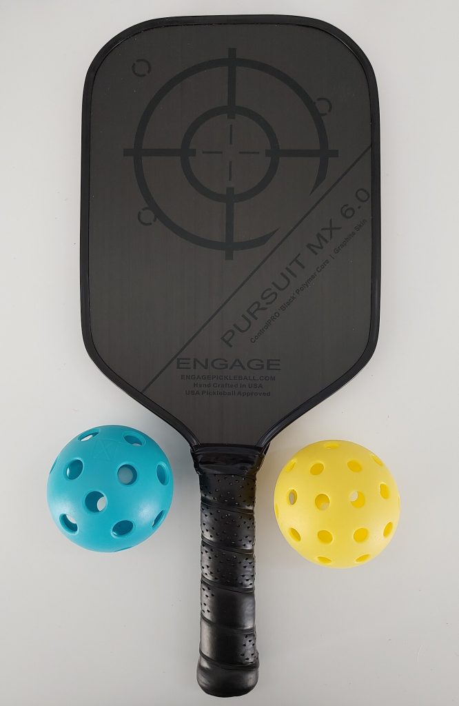 A pickleball paddle resting with two pickleballs
